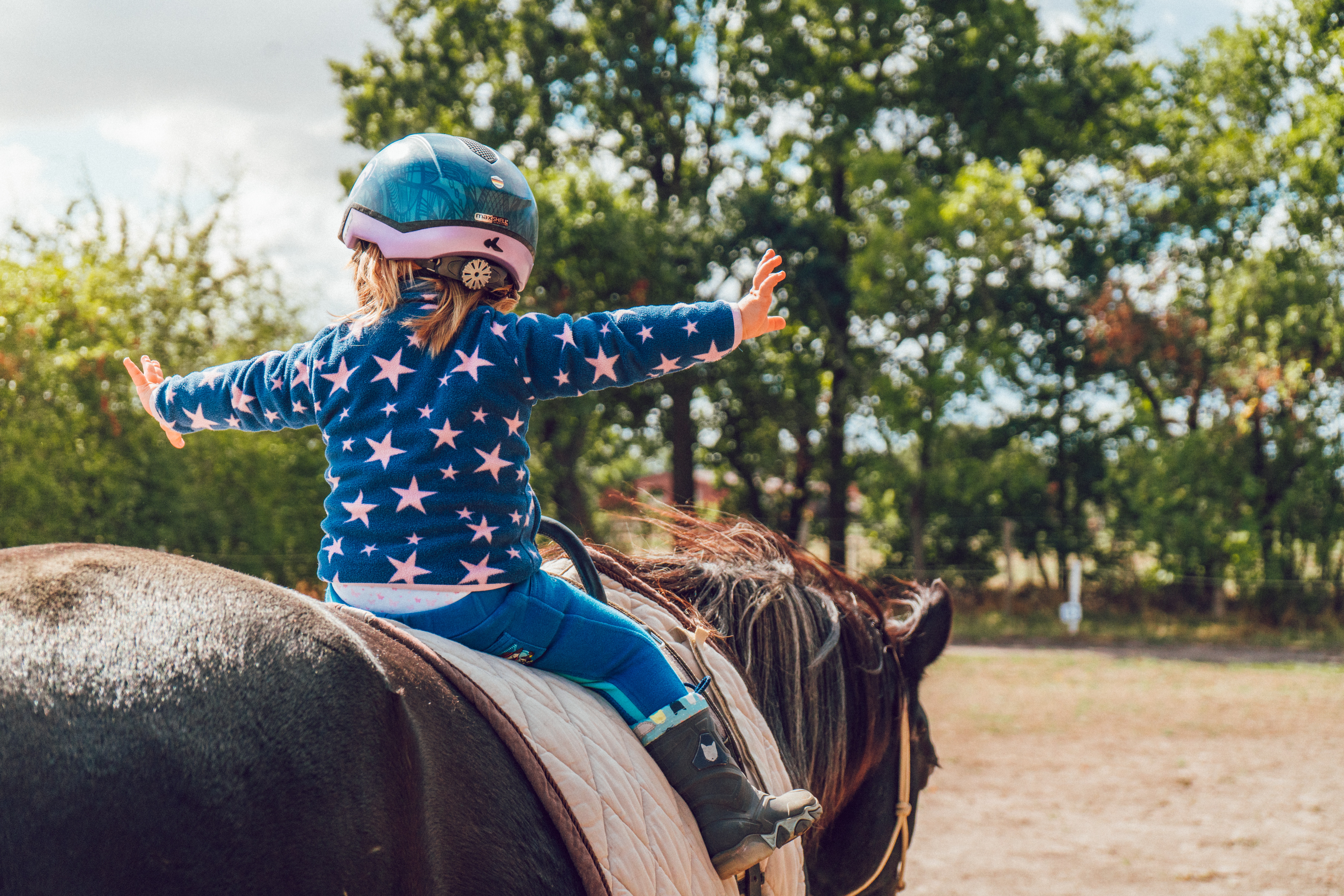 Kind met helm rijdt op een paard.